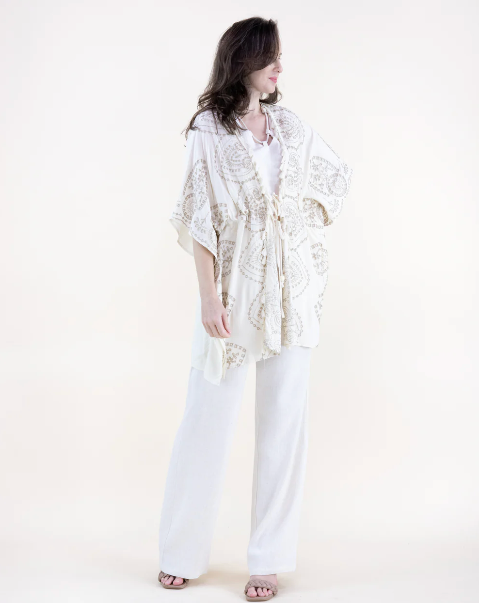 Woman wearing a white lace kimono-style garment on a plain background