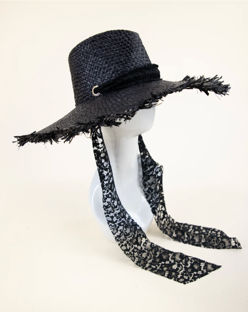 Black straw hat with decorative band and scarf on a mannequin head against a white background