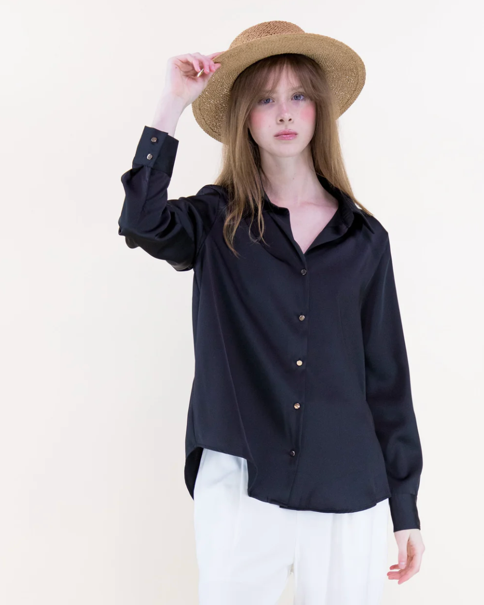 Person wearing a black shirt and white pants with a straw hat on a plain background