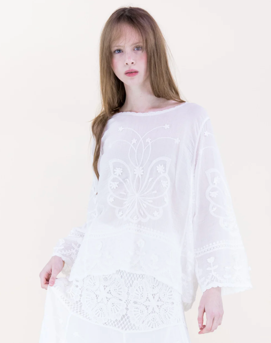 Woman wearing a white lace dress against a plain background