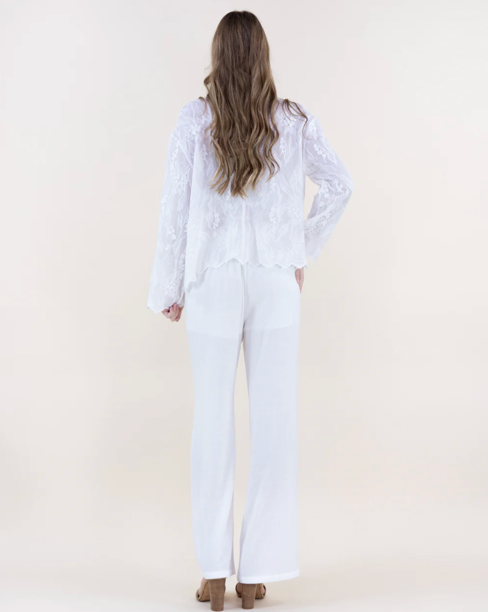 Person wearing a white outfit with long sleeves and pants on a plain background