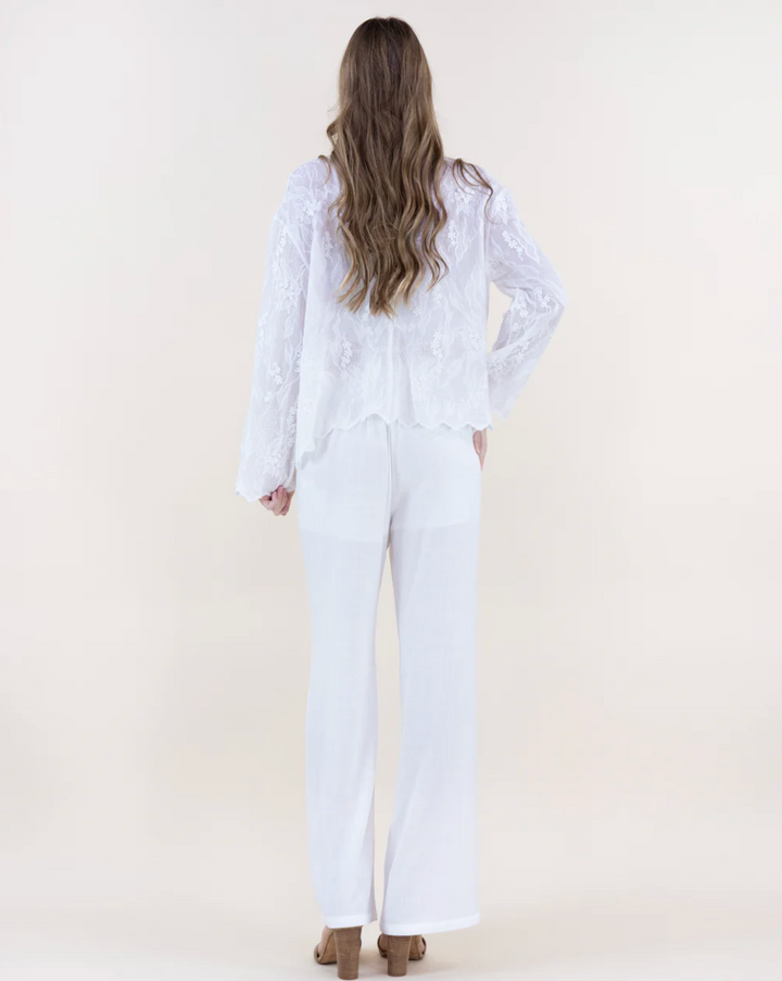 Person wearing a white outfit with long sleeves and pants on a plain background