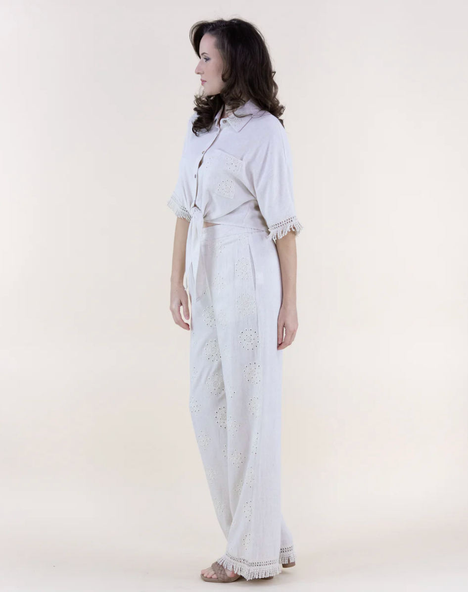 Woman wearing a white outfit with lace details on a plain background