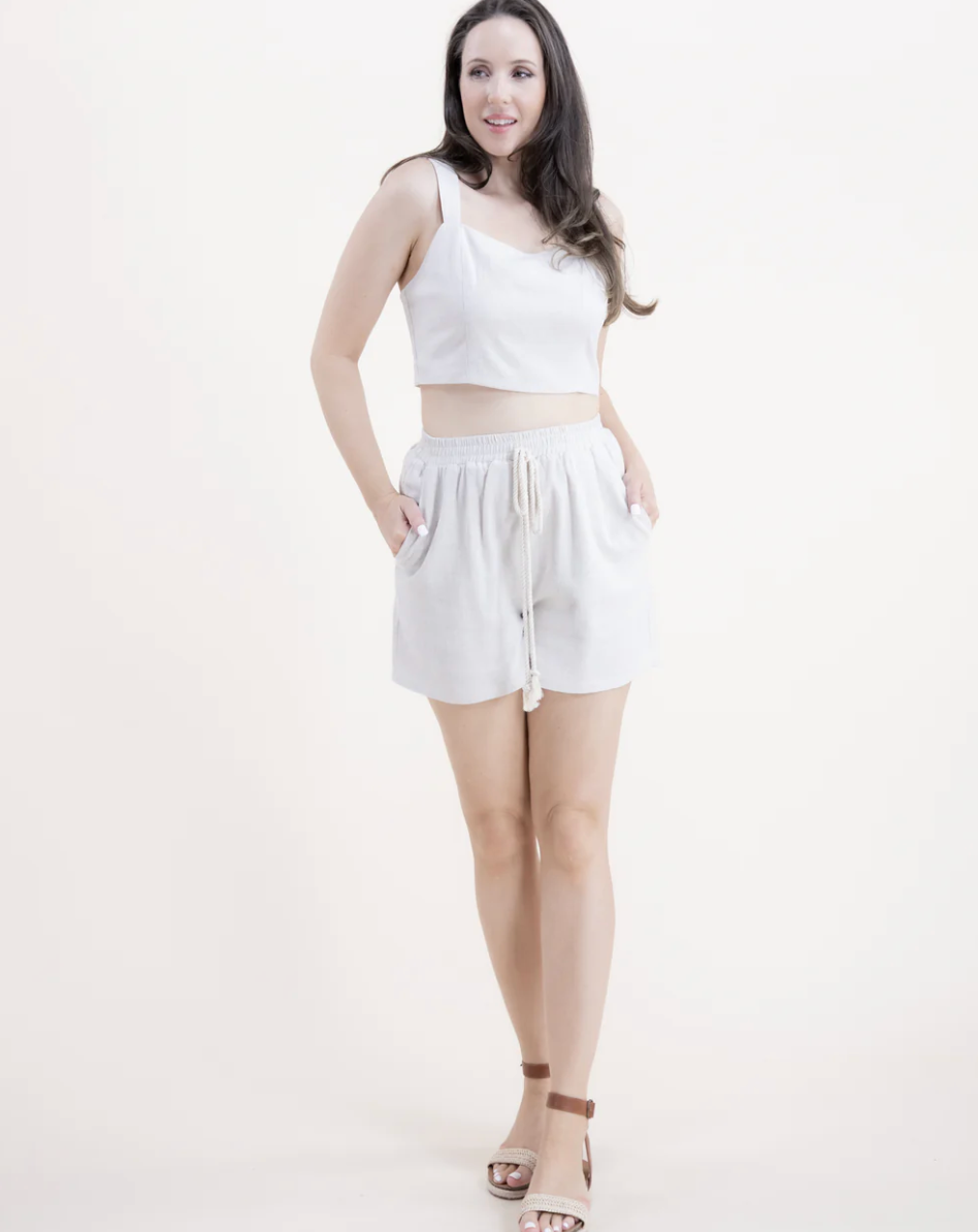 Woman wearing a white sleeveless top and shorts on a white background