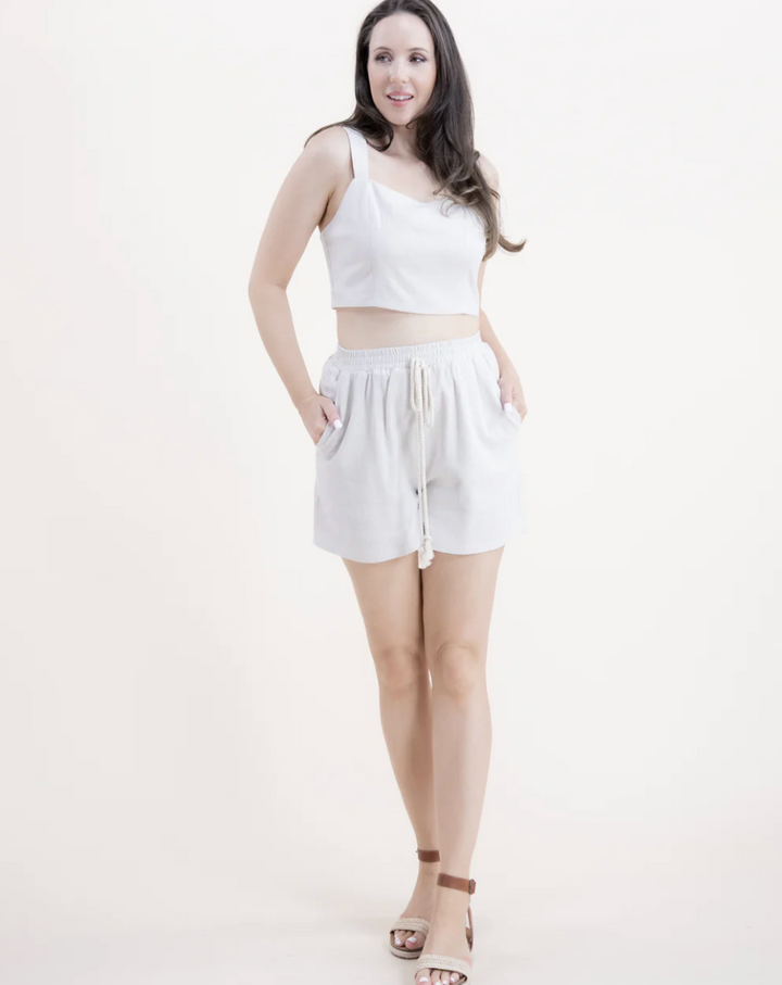 Woman wearing a white sleeveless top and shorts on a white background