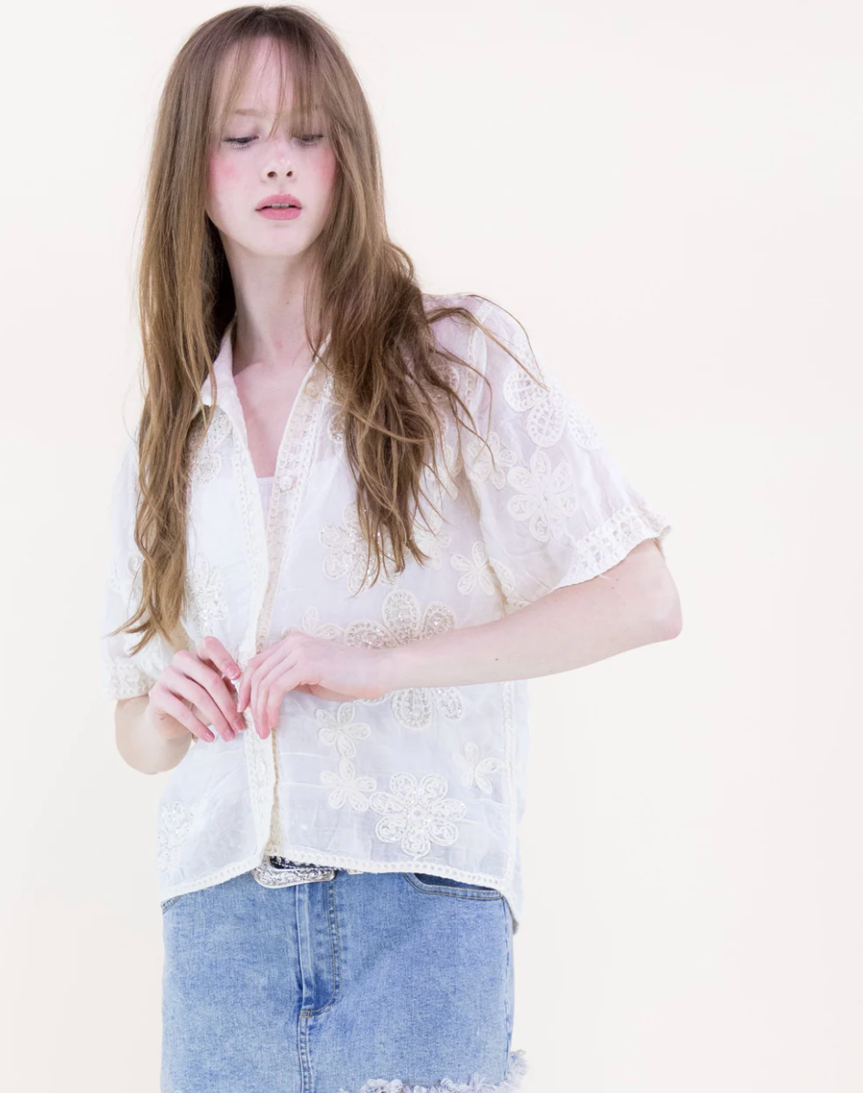 Woman wearing a white lace blouse and blue jeans on a plain background