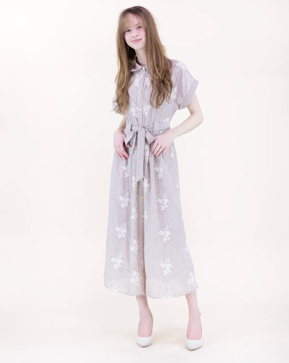Young girl wearing a beige floral dress on a white background