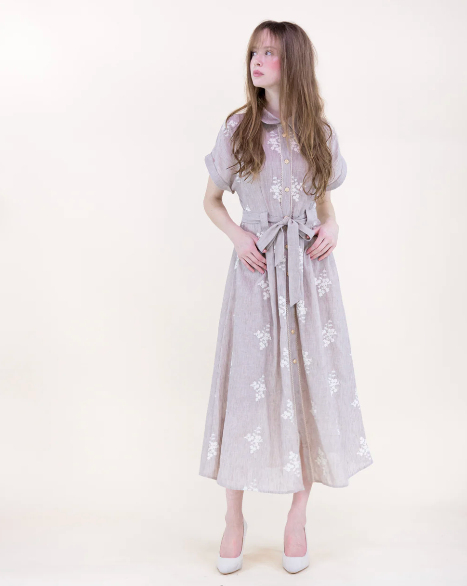 Woman wearing a light-colored dress with floral patterns on a white background