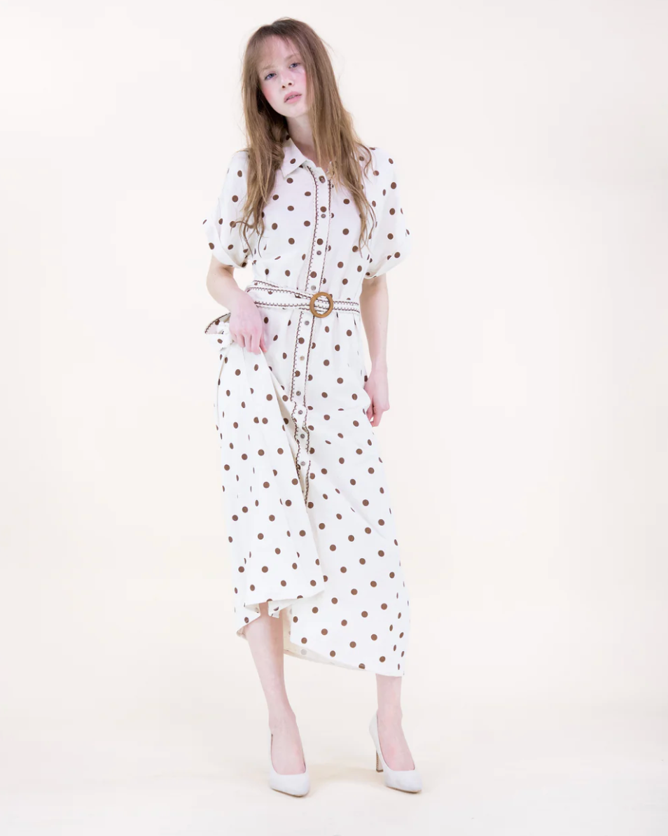 Woman wearing a white dress with brown polka dots on a white background