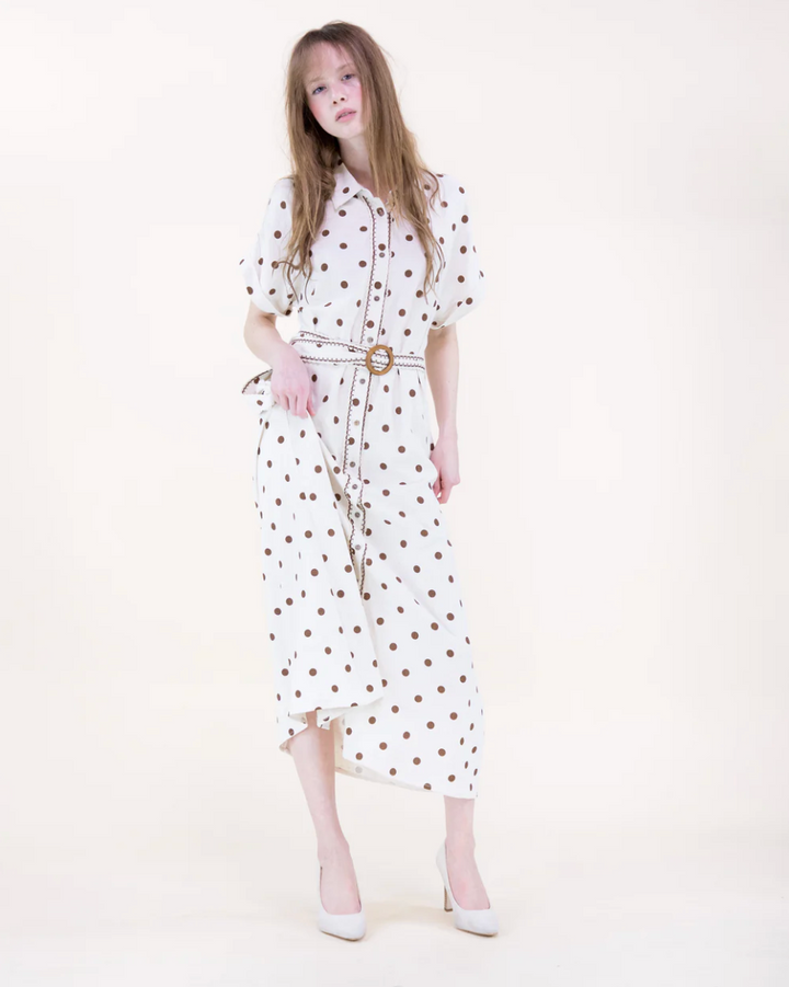 Woman wearing a white dress with brown polka dots on a white background