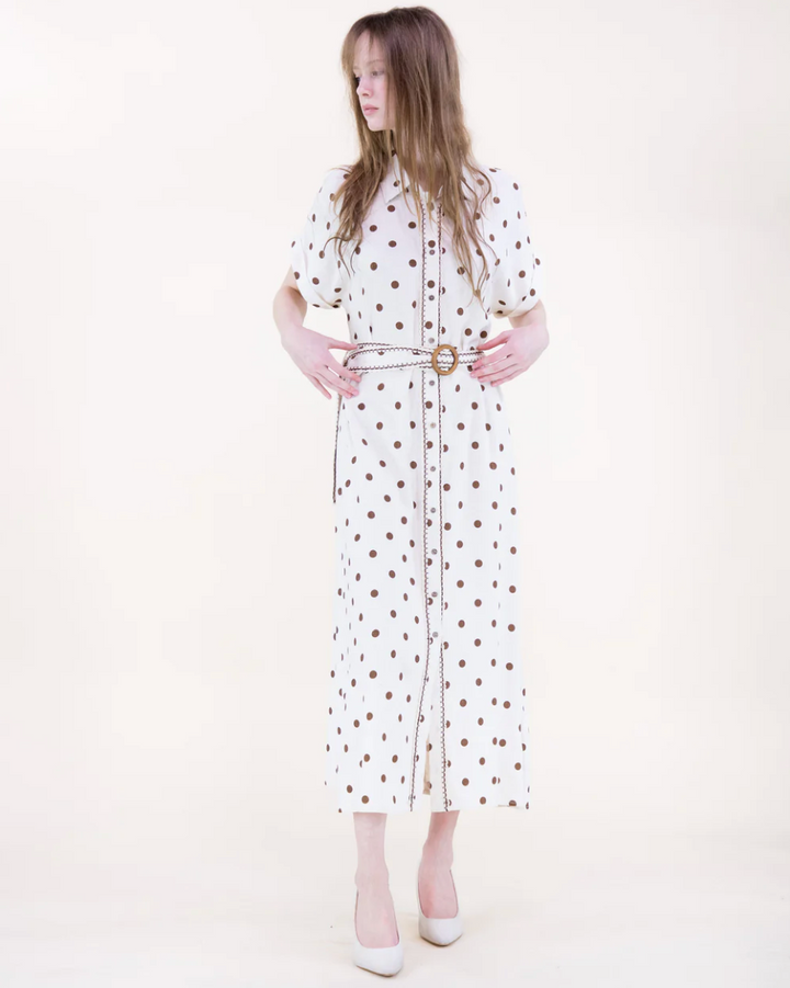 Woman wearing a white dress with brown polka dots on a white background