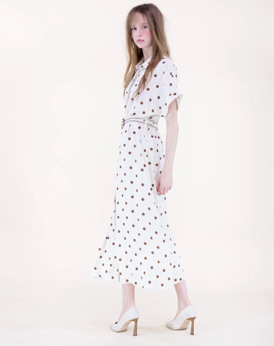 Woman wearing a white dress with red polka dots on a white background