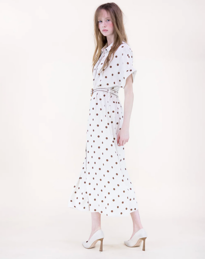 Woman wearing a white dress with red polka dots on a white background