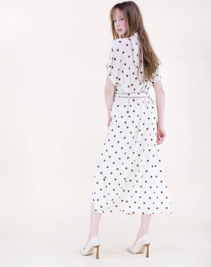 Woman wearing a white dress with red polka dots on a white background