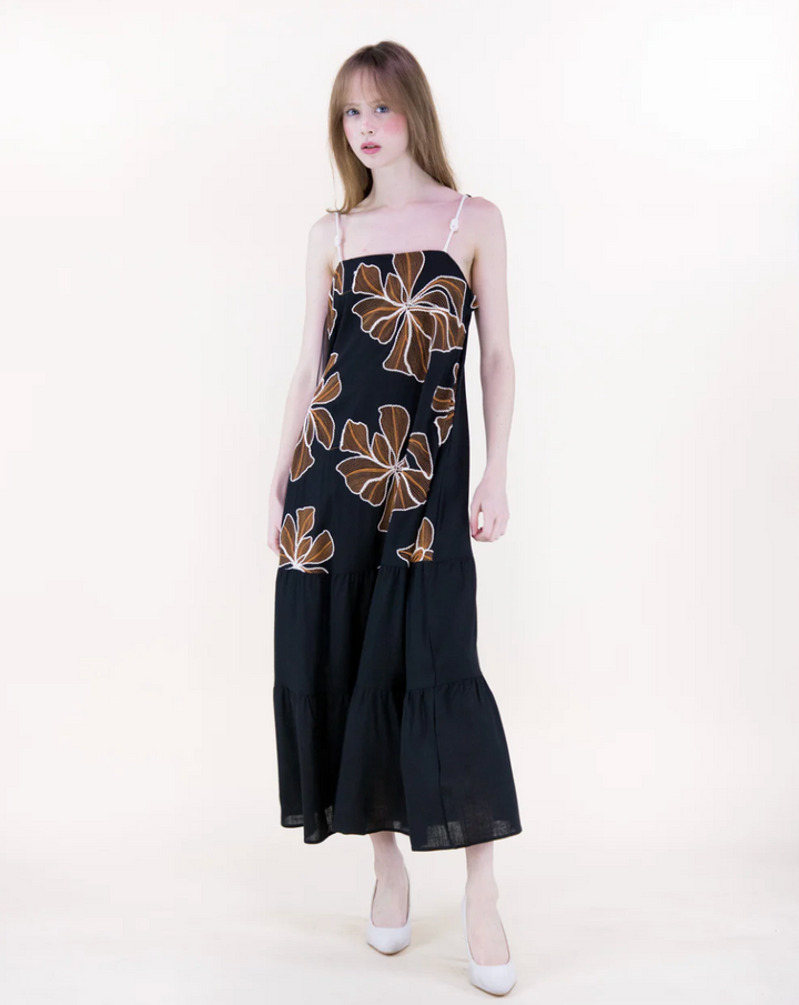 Woman wearing a black dress with floral patterns on a white background