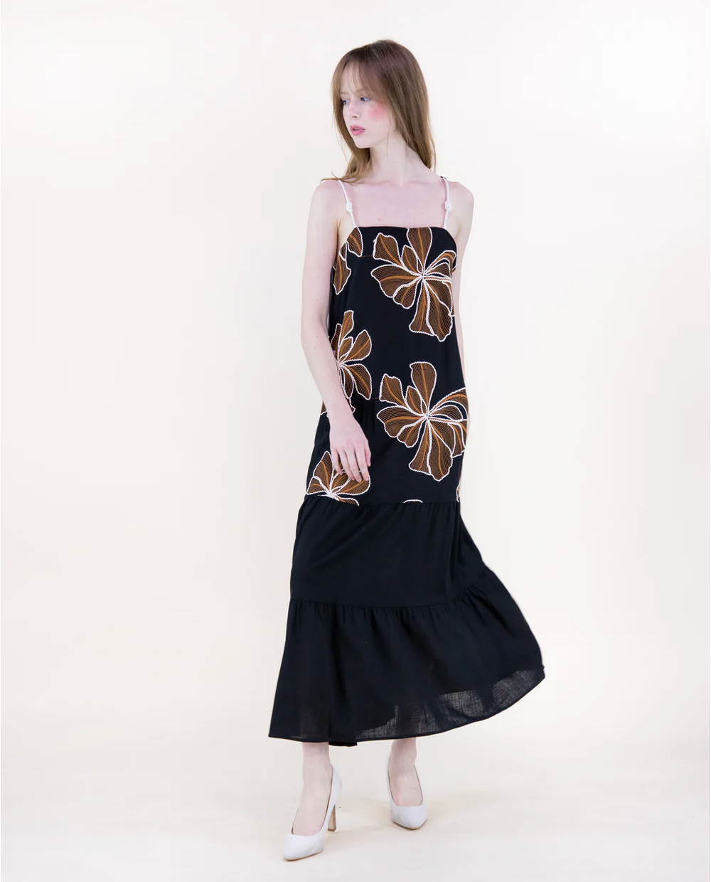 Woman wearing a black dress with floral patterns on a white background