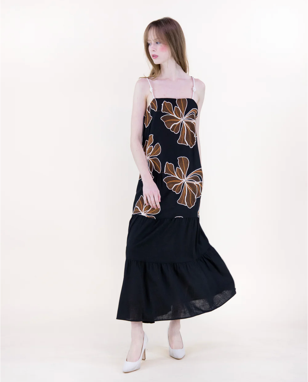 Woman wearing a black dress with floral patterns on a white background
