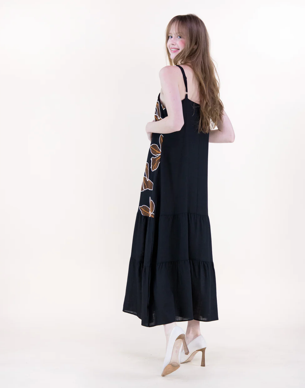 Woman wearing a black dress with floral patterns on a white background