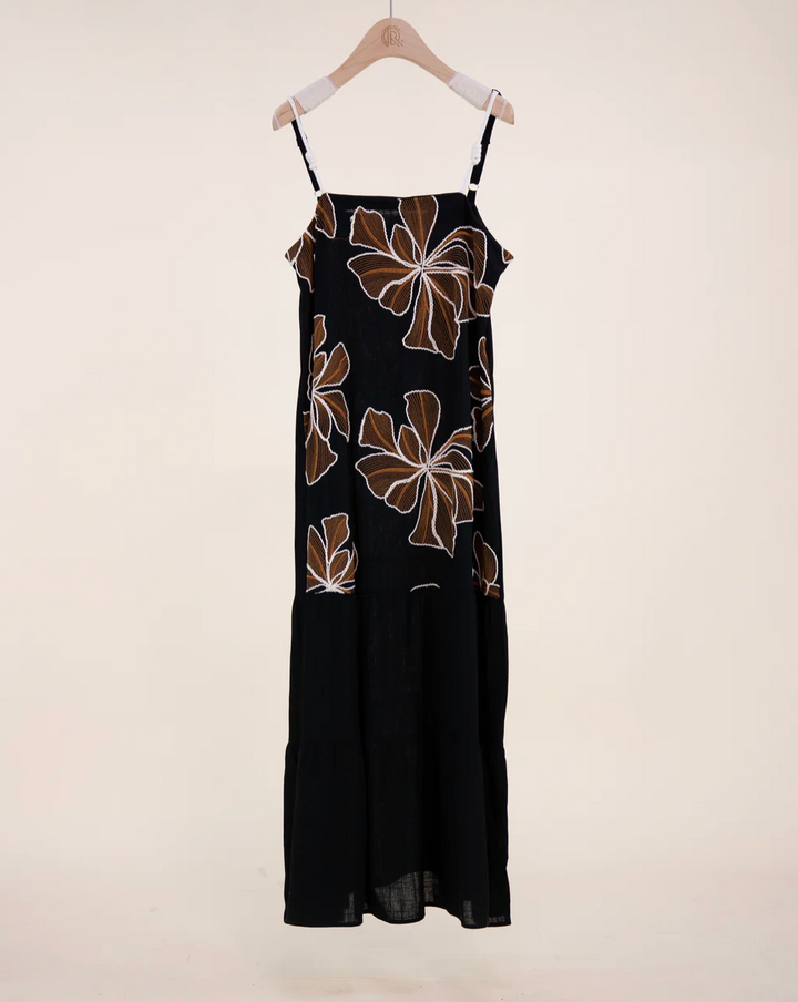 Black dress with brown floral patterns on a hanger against a white background