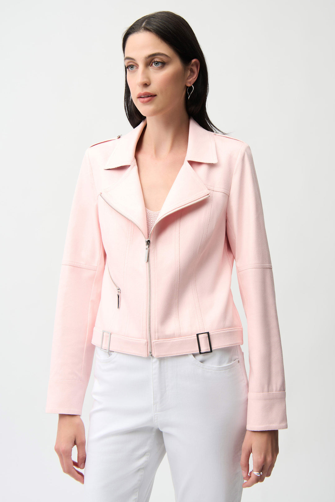 Woman wearing a pink jacket and white pants on a light gray background