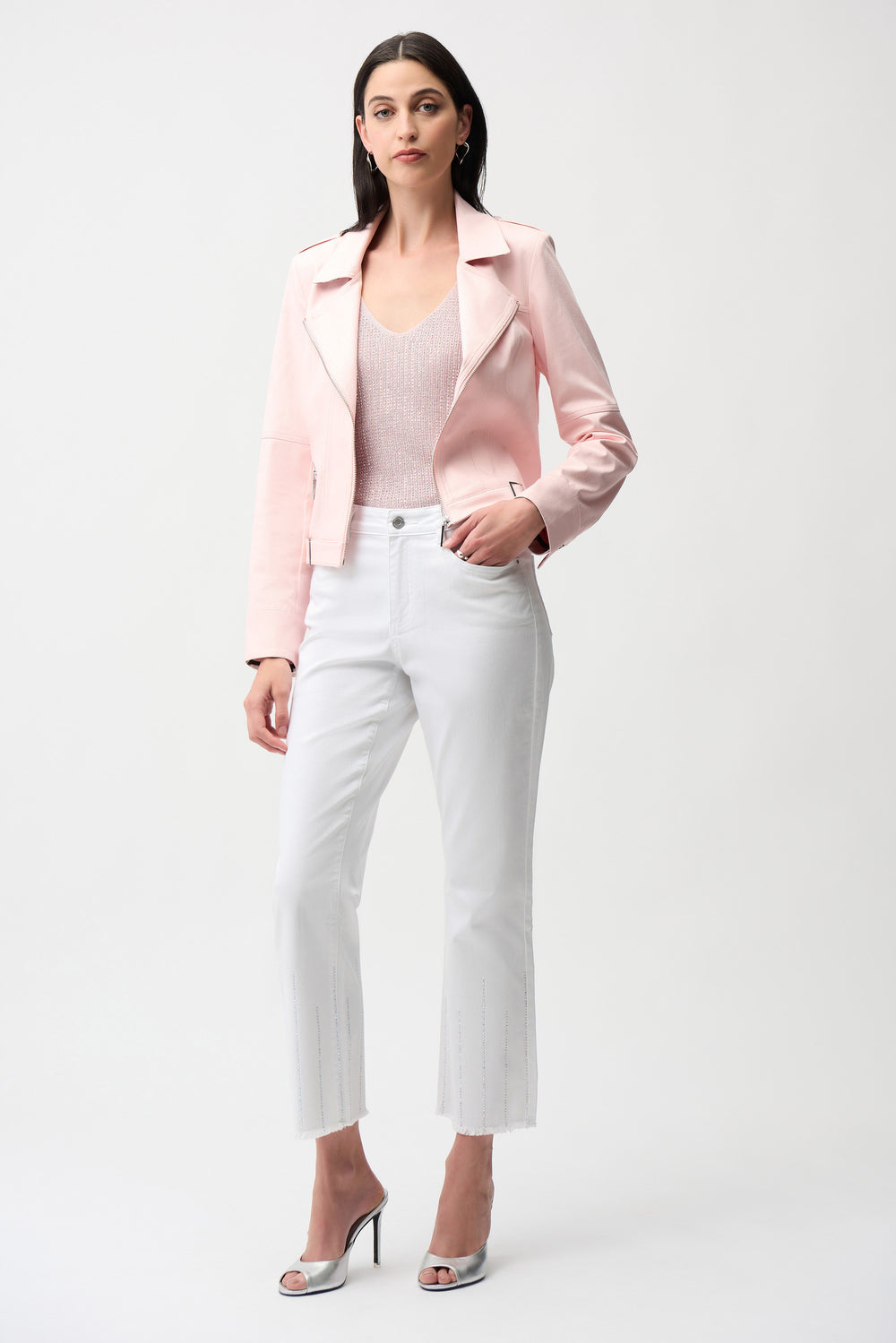 Woman wearing a pink blazer, white top, and white pants on a white background