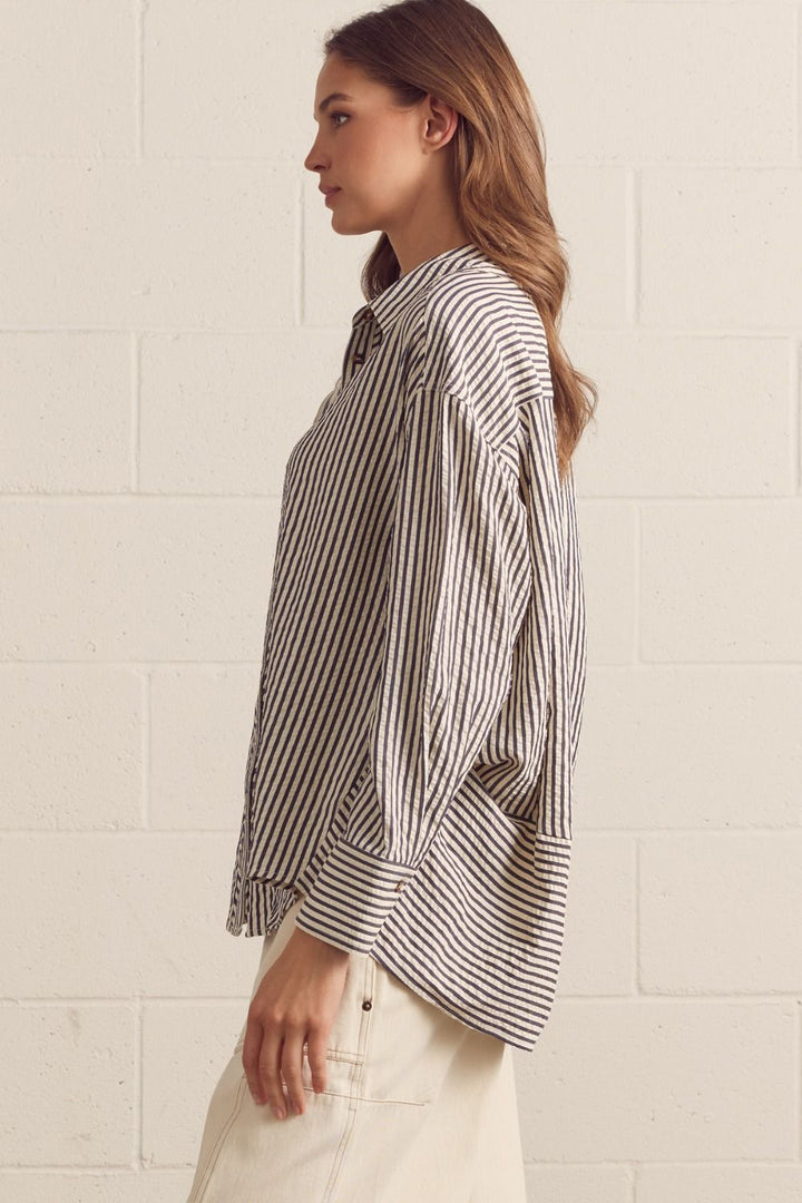 Woman wearing a striped shirt against a white tiled wall