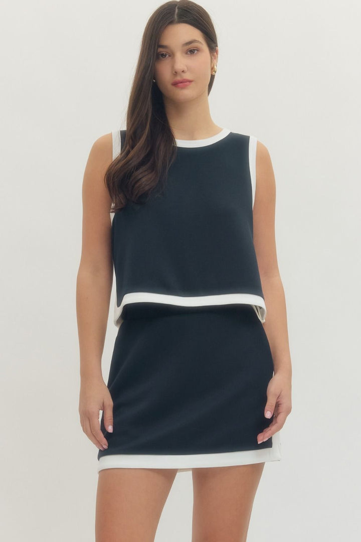Woman wearing a navy and white dress on a plain background