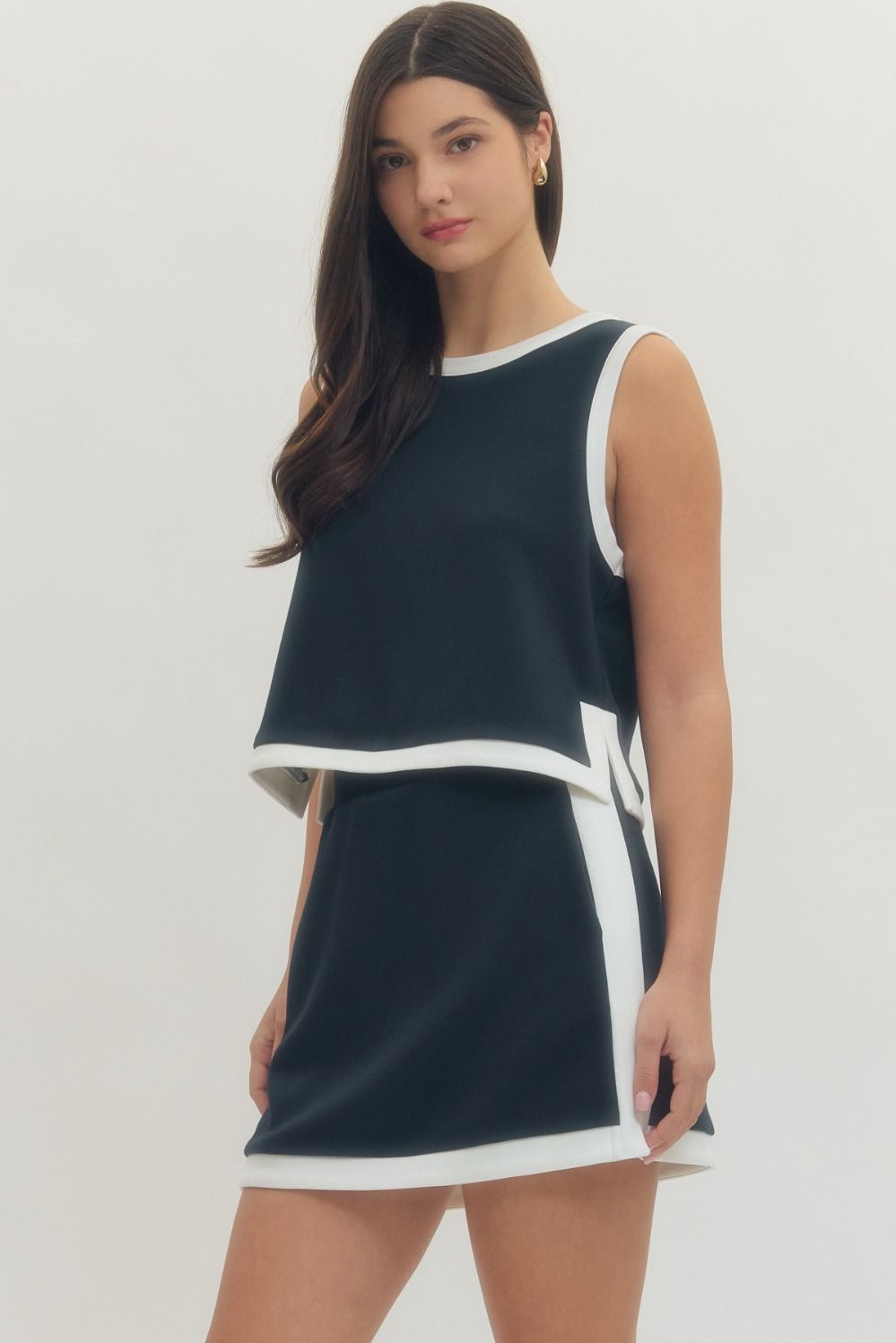 Woman wearing a navy dress with white trim on a light gray background