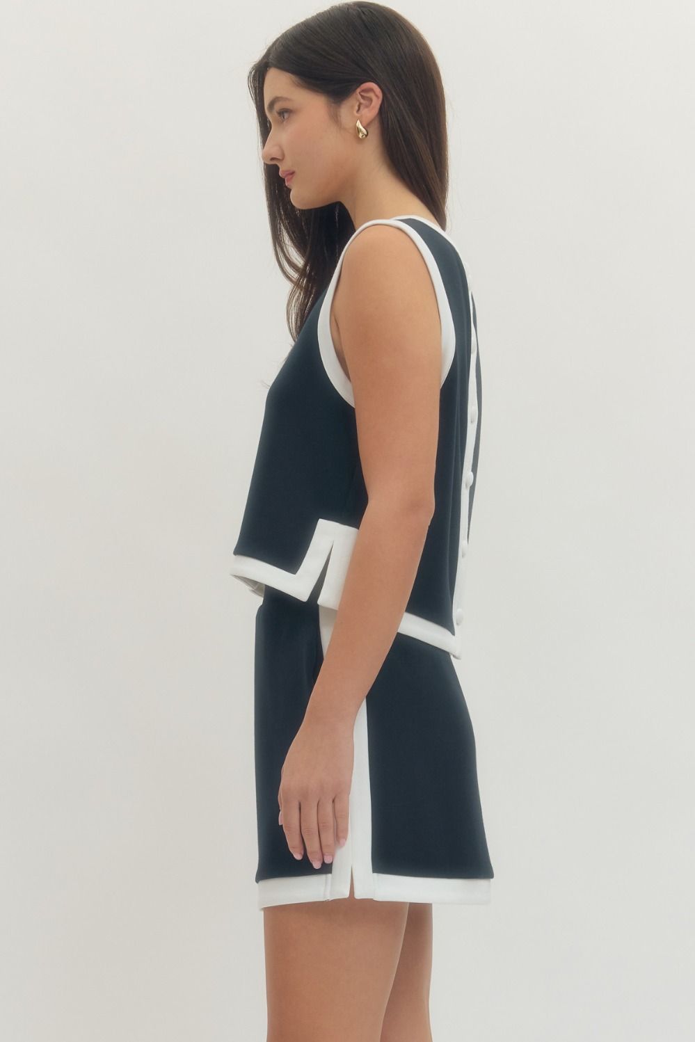 Woman wearing a navy dress with white trim on a plain background