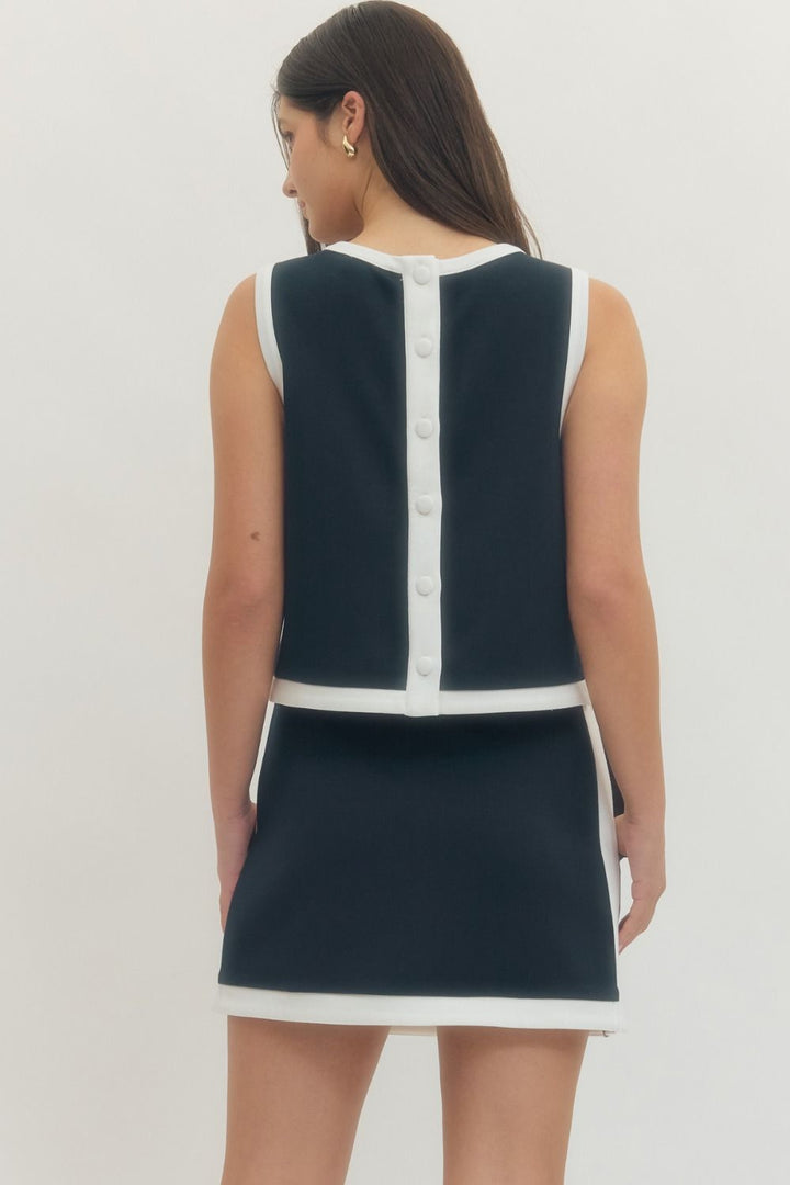 Navy and white dress with button details on a plain background