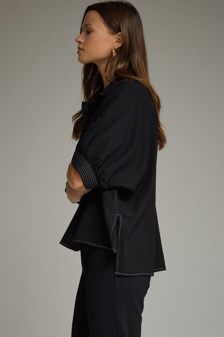 Woman wearing a black outfit against a plain background