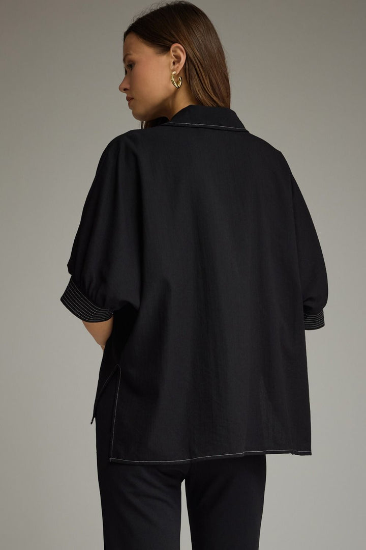 Person wearing a black outfit with a neutral background