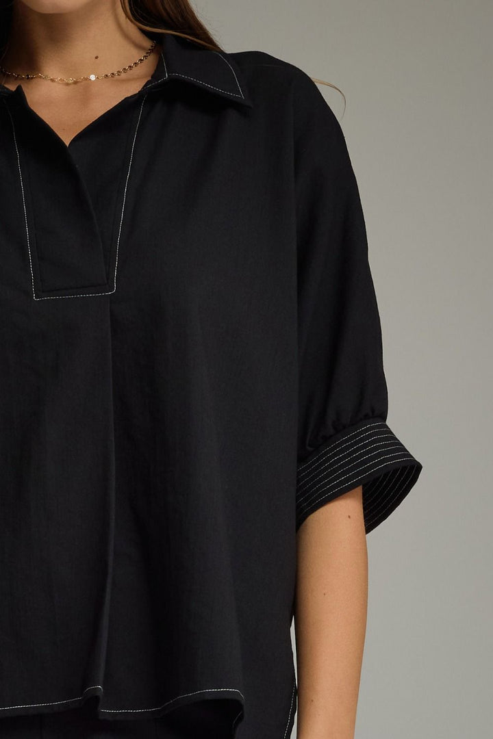 Black shirt worn by a person, close-up on the collar and sleeve.