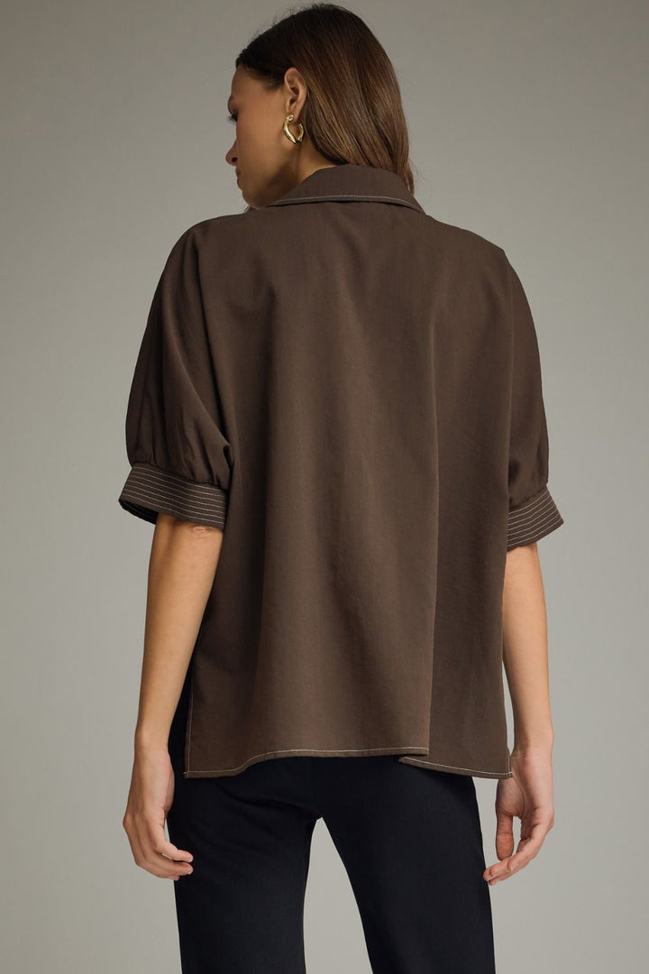 Woman wearing a brown blouse against a neutral background