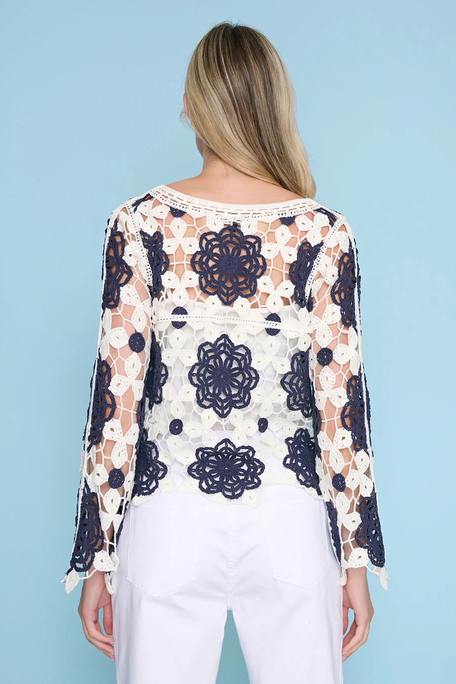 Woman wearing a floral lace top against a blue background