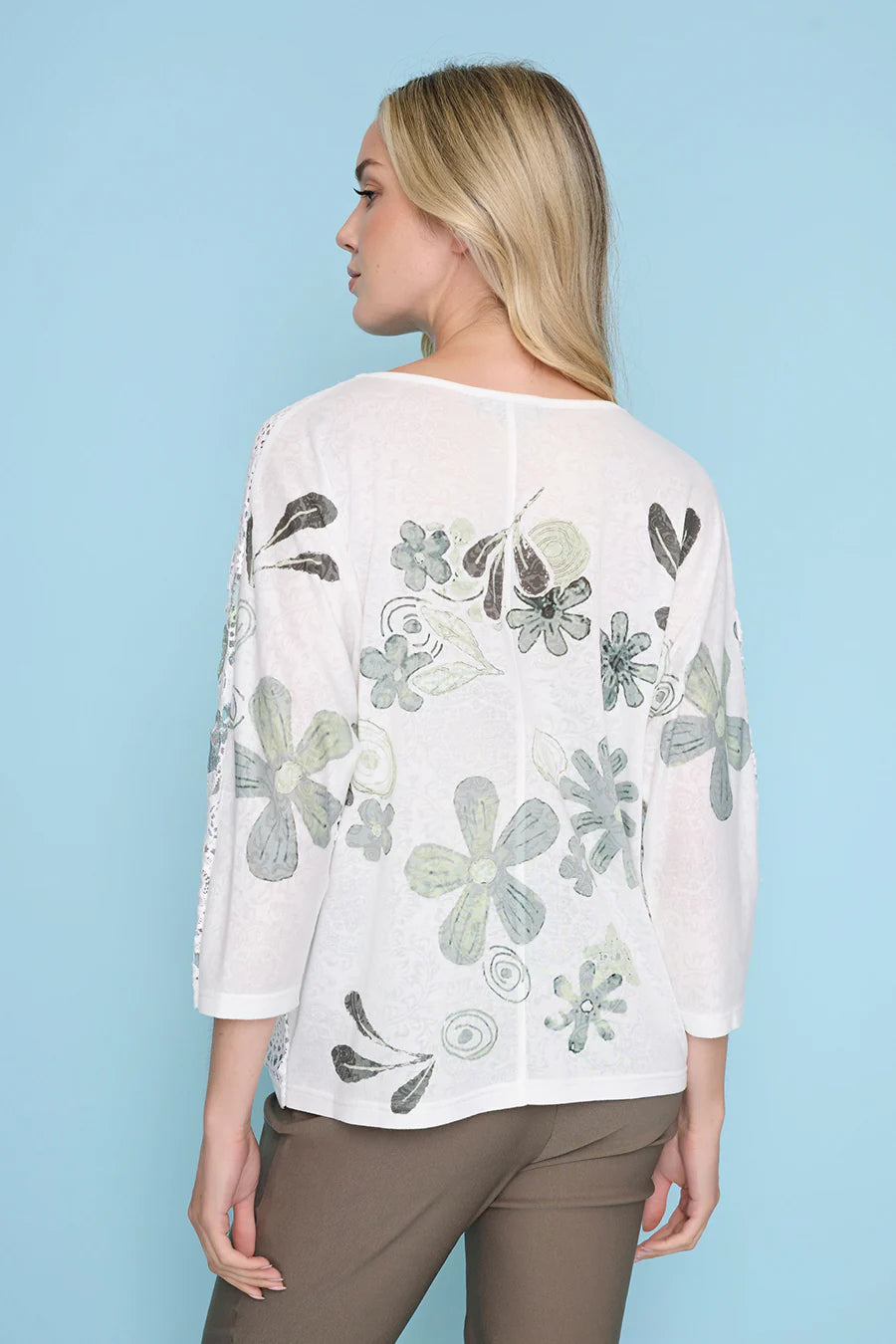 Woman wearing a white blouse with floral patterns on a light blue background