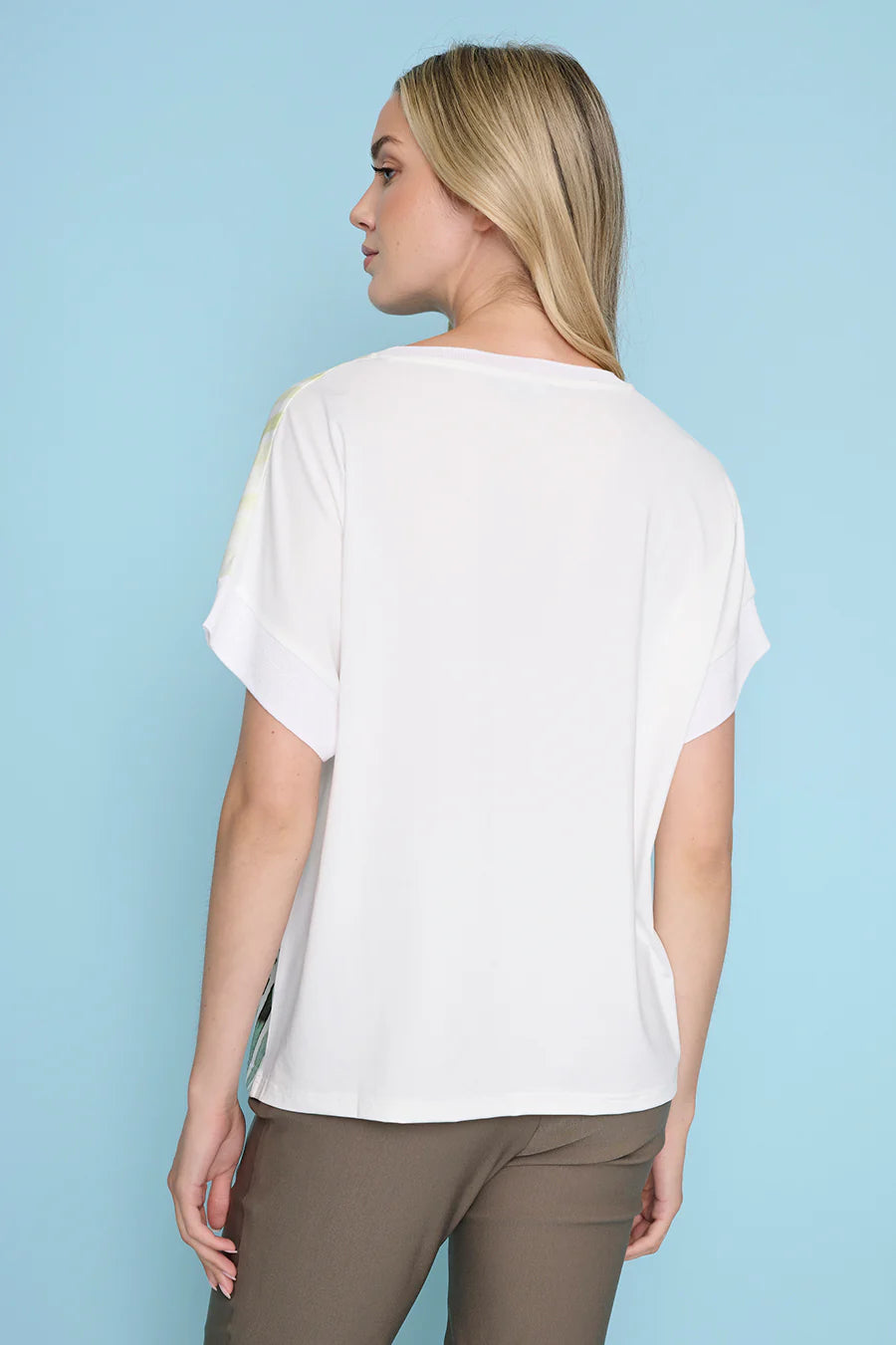 Woman wearing a white t-shirt and brown pants against a light blue background