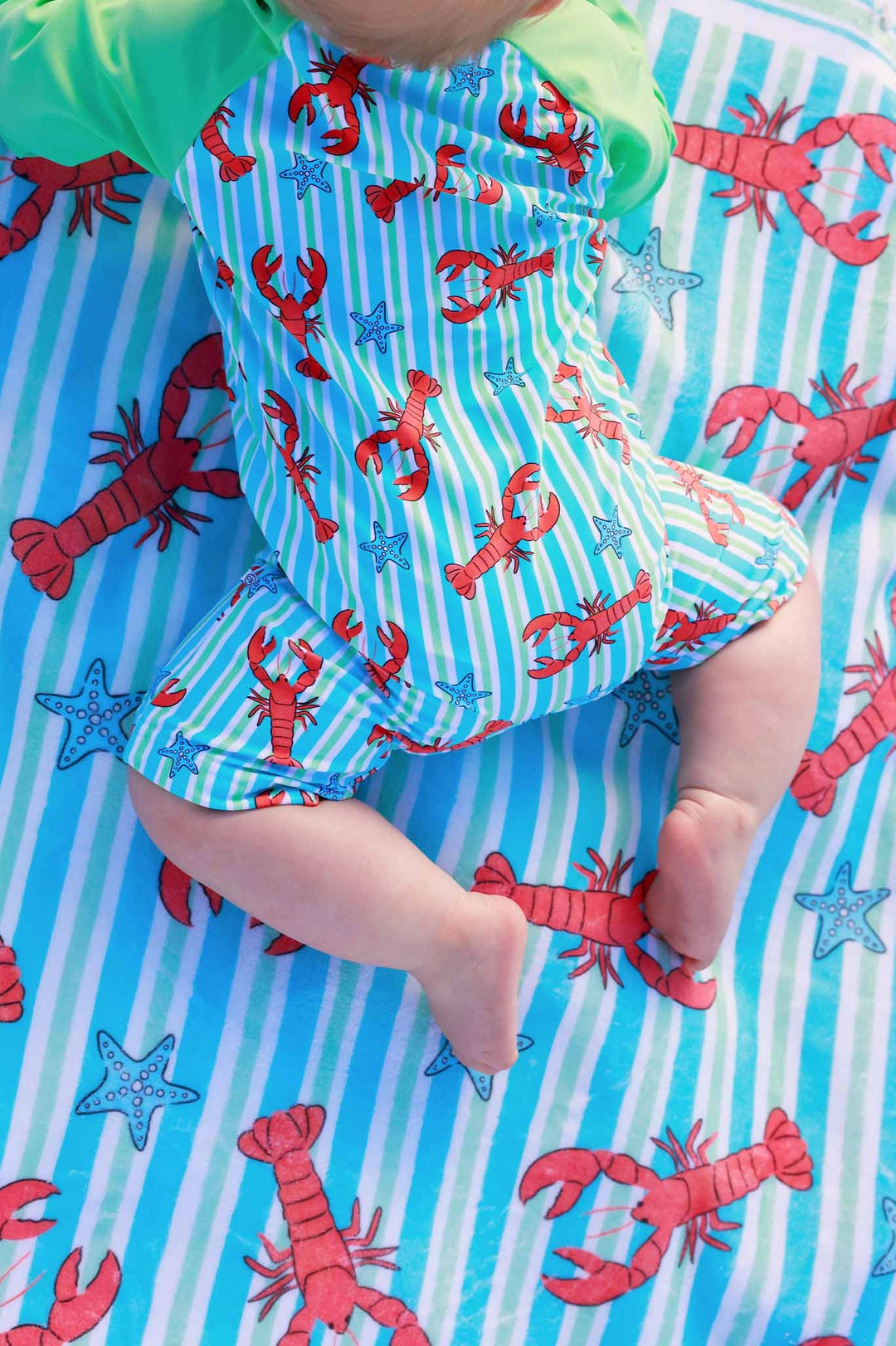 Baby in a lobster-themed outfit on a matching blanket