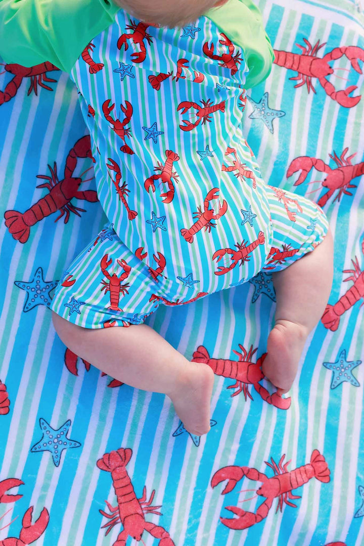 Baby in a lobster-themed outfit on a matching blanket