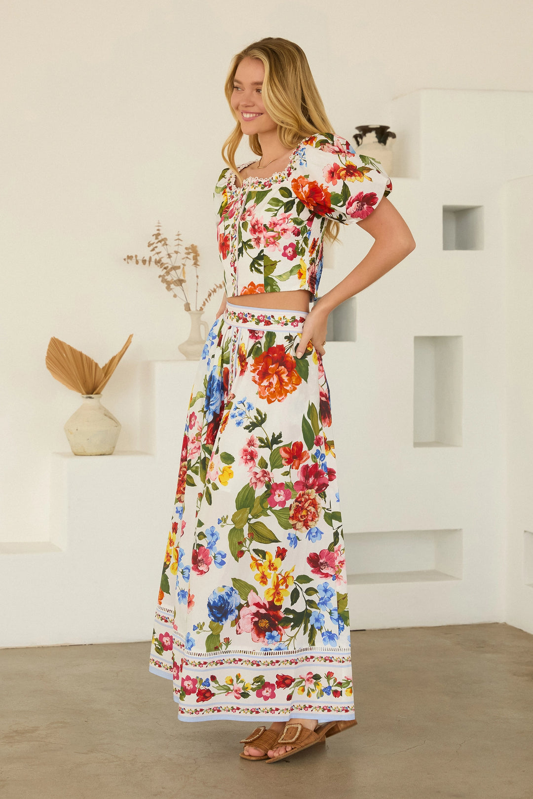 Woman wearing a floral dress standing in a minimalistic room.