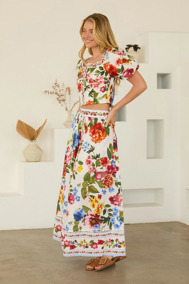 Woman wearing a floral dress standing in a minimalistic room.