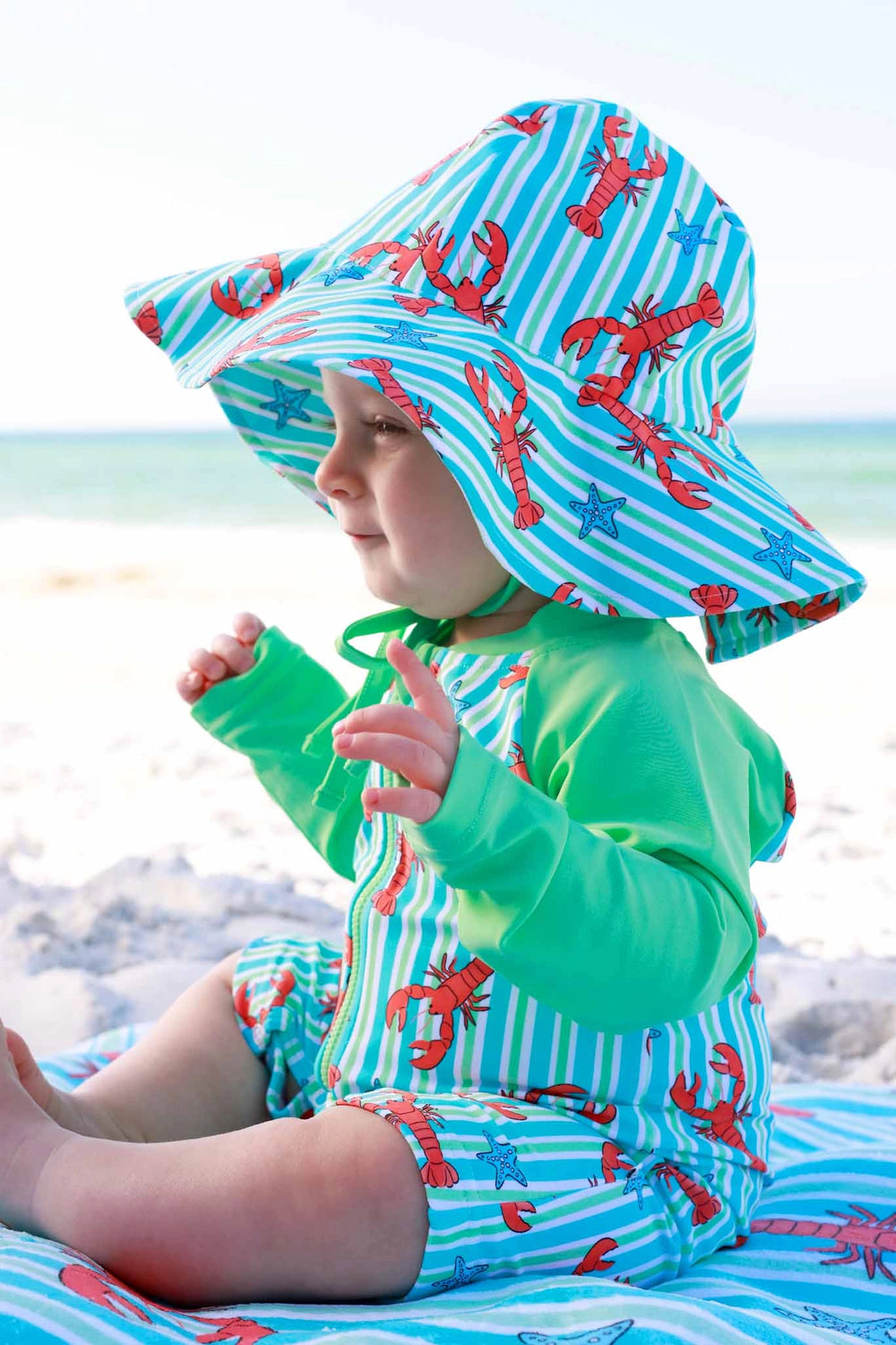 Child wearing a colorful sun hat and swimsuit on a beach