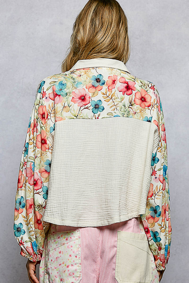 Person wearing a floral kimono-style jacket over a white shirt with a gray background