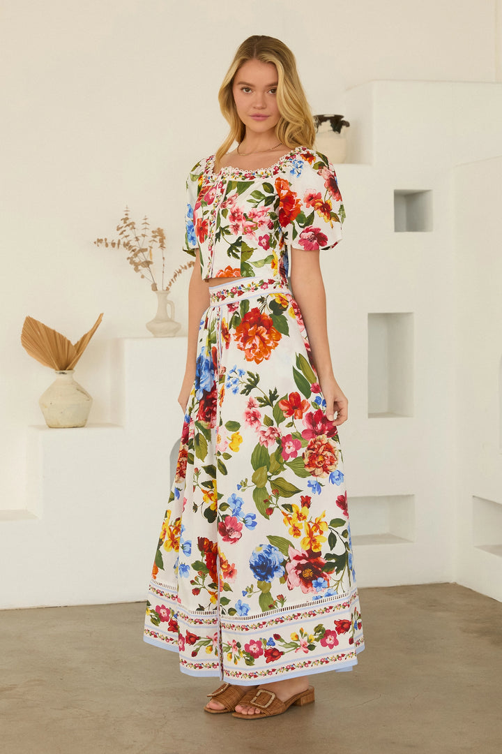 Woman wearing a colorful floral dress in a minimalistic room.