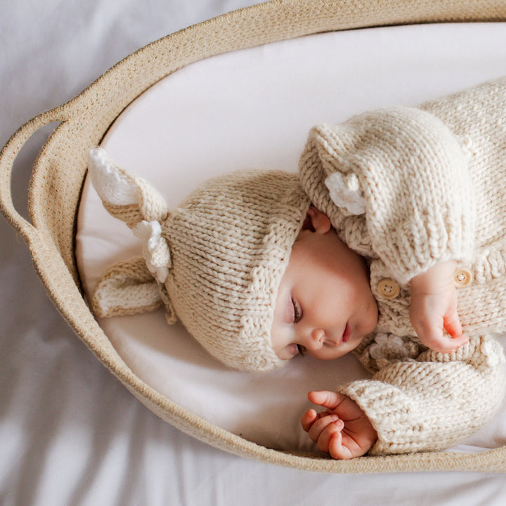 Sleeping baby in a basket wearing the Blossom Bunny Baby Hat and Blossom Baby Cardigan