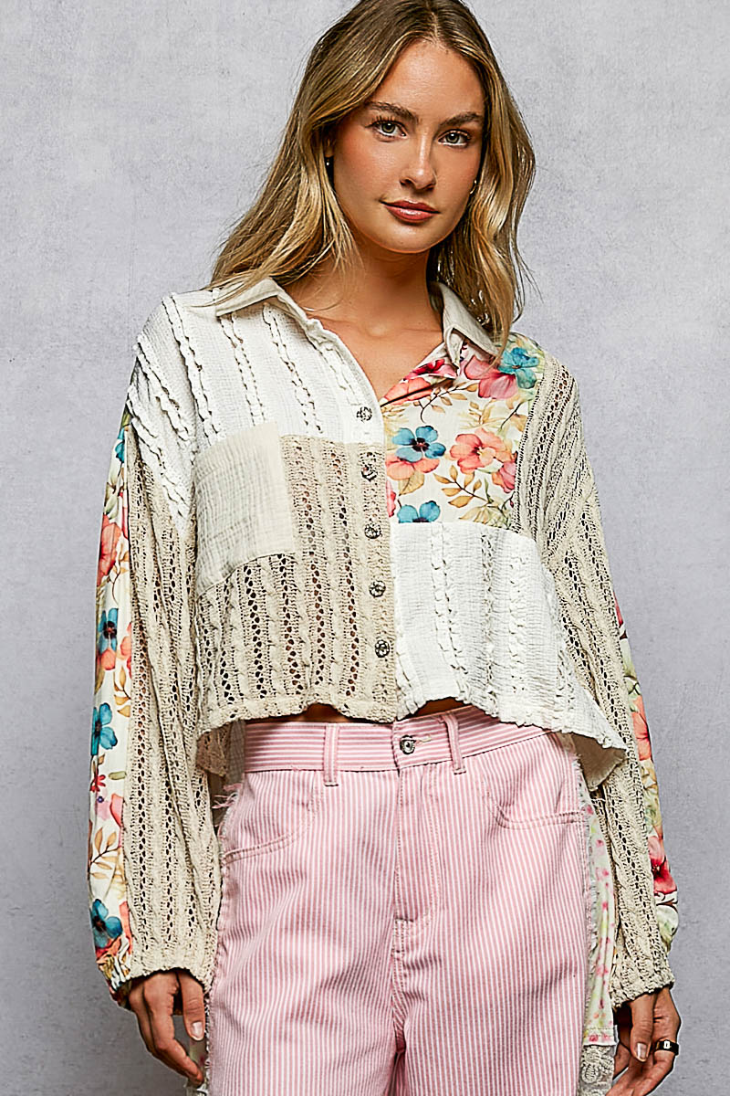 Woman wearing a floral blouse, lace cardigan, and pink pants against a gray background