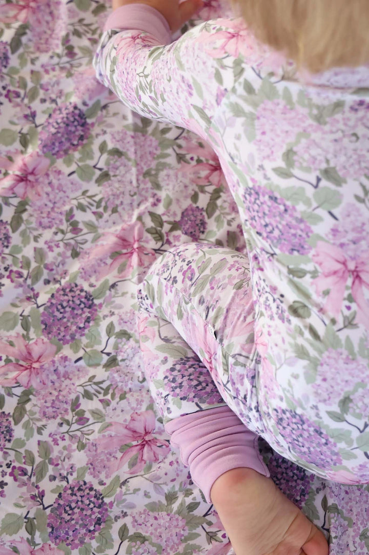 Child wearing a floral onesie on a floral blanket