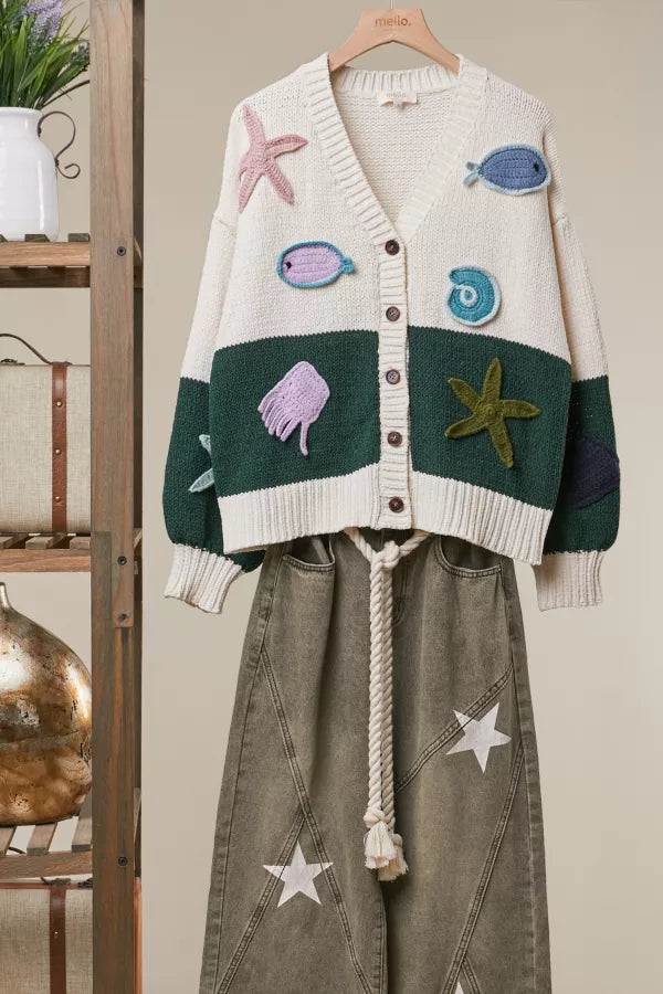Tide Pool Cardigan in ivory and hunter green with crochet sea creature appliqués, front view