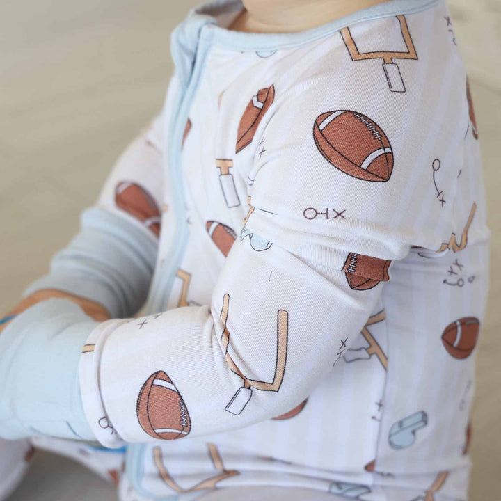 Baby in a onesie with football pattern on a neutral background