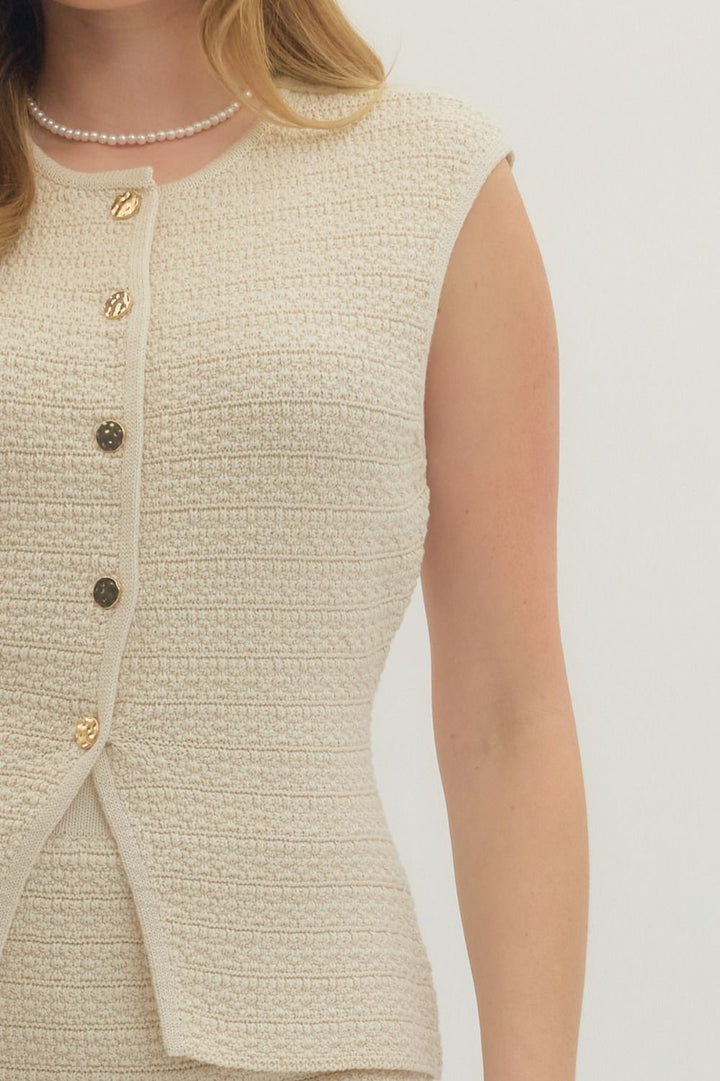 Close-up of a beige textured sleeveless top with buttons on a white background